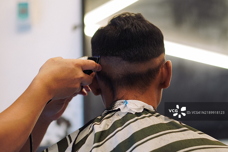 理发师正在用电推剪为男顾客剪一个新发型图片素材