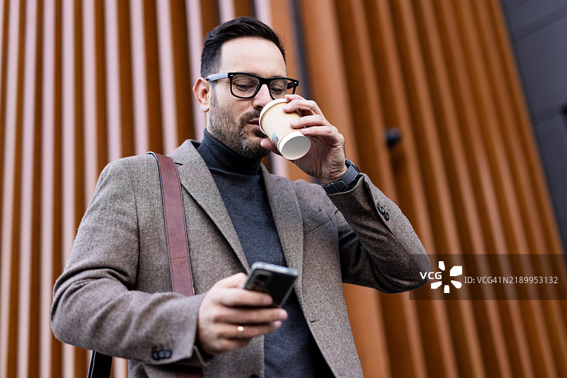 商人在办公室外喝咖啡并使用智能手机图片素材