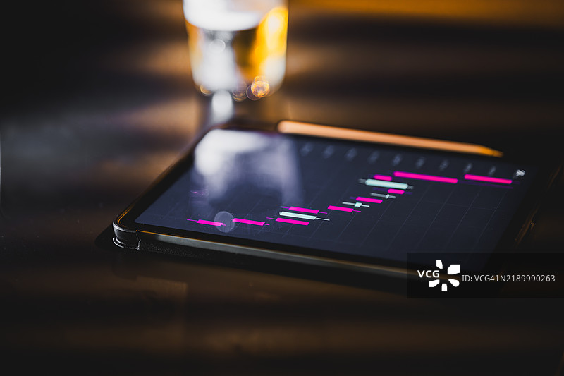 平板电脑显示着增长的统计图表，旁边是一杯水图片素材