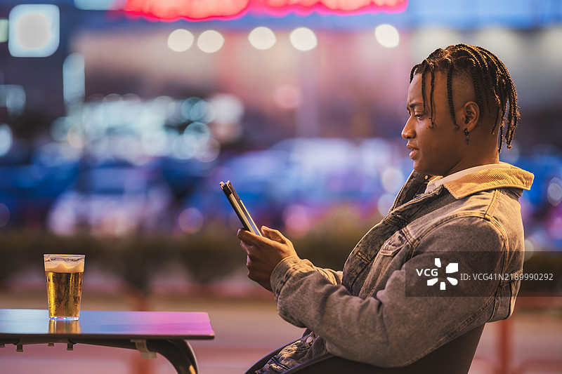 年轻的拉丁裔男子在酒吧里夜间使用平板电脑图片素材