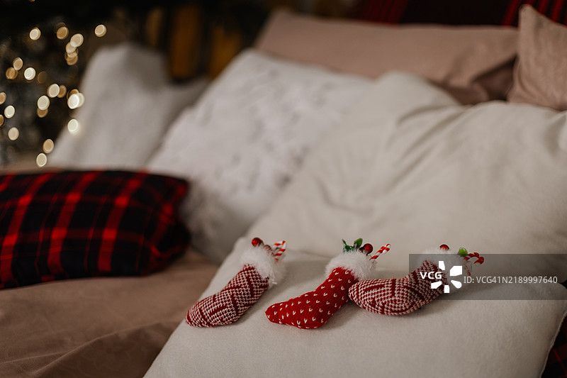 三只带有糖果手杖装饰的圣诞袜躺在床上。图片素材