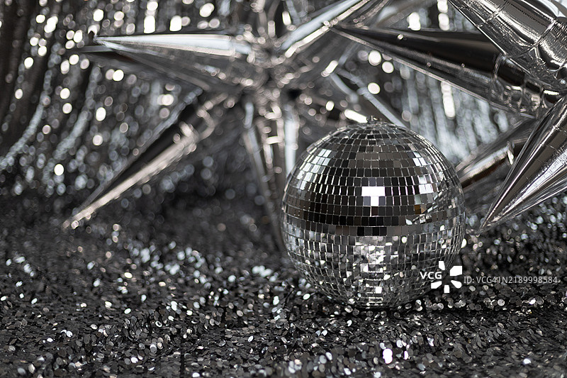 迪斯科球与大型银色箔气球星星在亮片布料上。图片素材