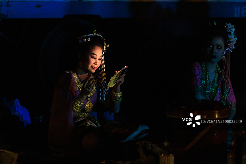 在手机的光线下，一位泰国舞者正在化妆。图片素材