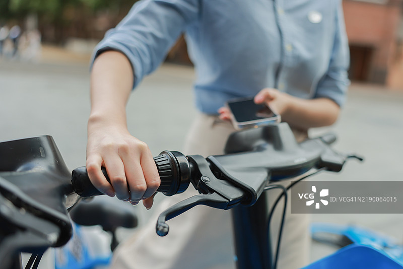 女人用手机解锁公共自行车图片素材