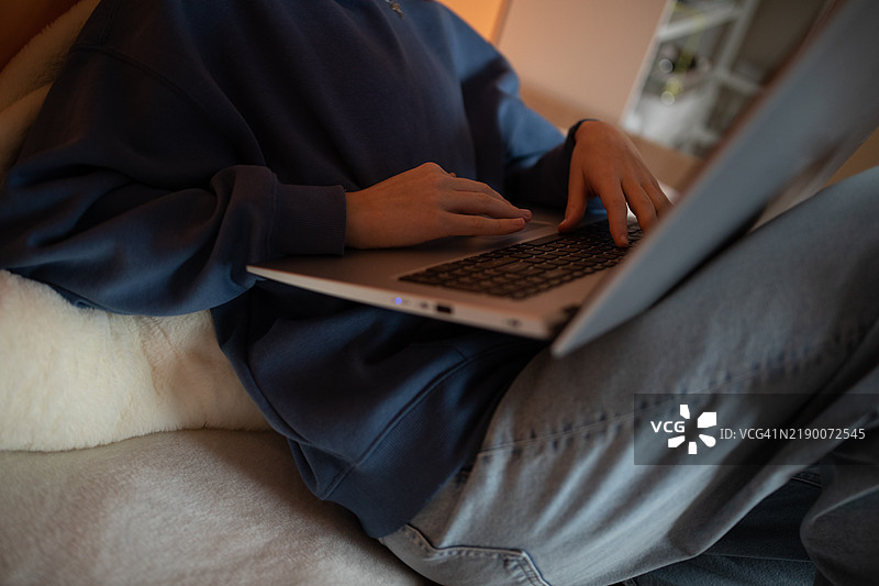 在温暖舒适的卧室氛围中使用笔记本电脑工作。图片素材