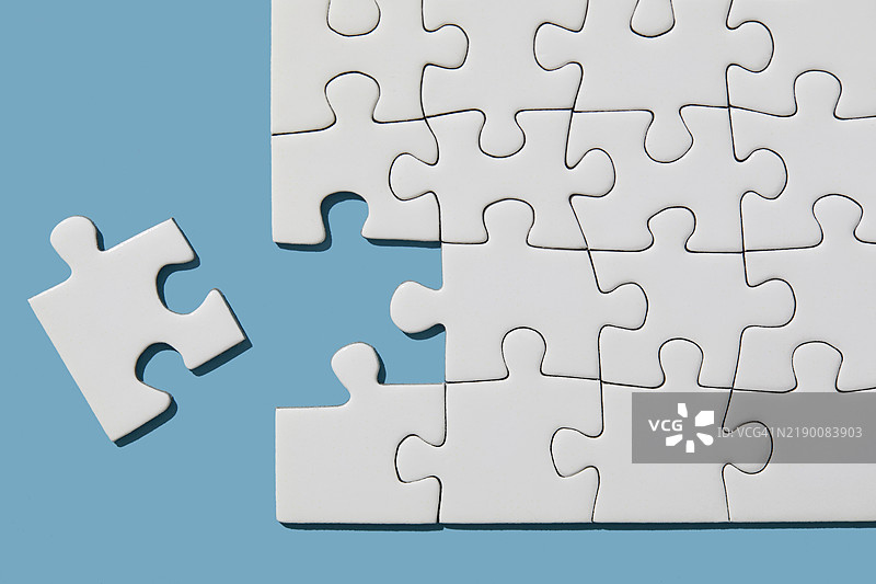 蓝色背景上的拼图缺了一块拼图。图片素材