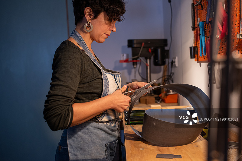 玻璃工艺师在她的工作室里切割金属板图片素材