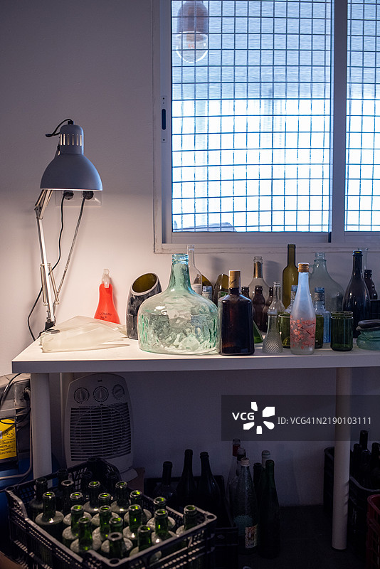 玻璃工匠在工作台上整理瓶子和罐子图片素材