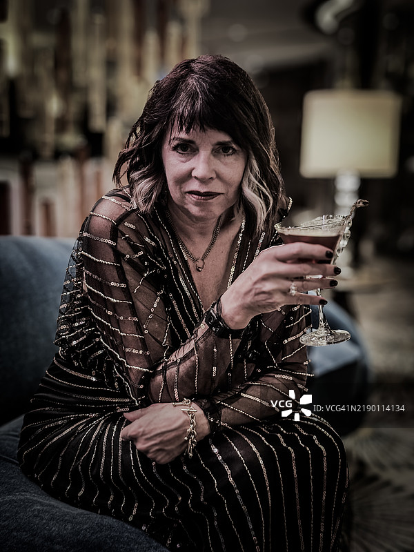 优雅的女性手持马提尼酒。图片素材