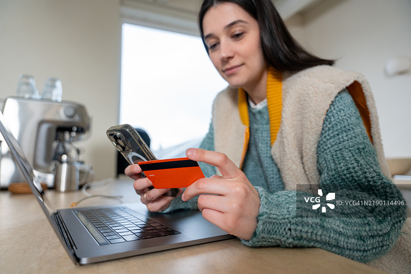 年轻女性使用信用卡和智能手机进行在线购物图片素材
