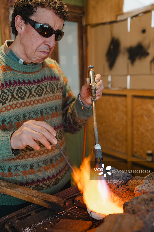 珠宝匠在工作室用喷灯熔化黄金图片素材