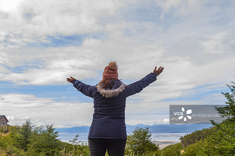 时尚的非洲裔成熟背包女游客在阿根廷乌斯怀亚享受自由，拥抱火地岛的风景。图片素材