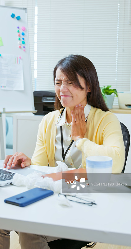 亚洲女性在办公室表现出感冒症状图片素材