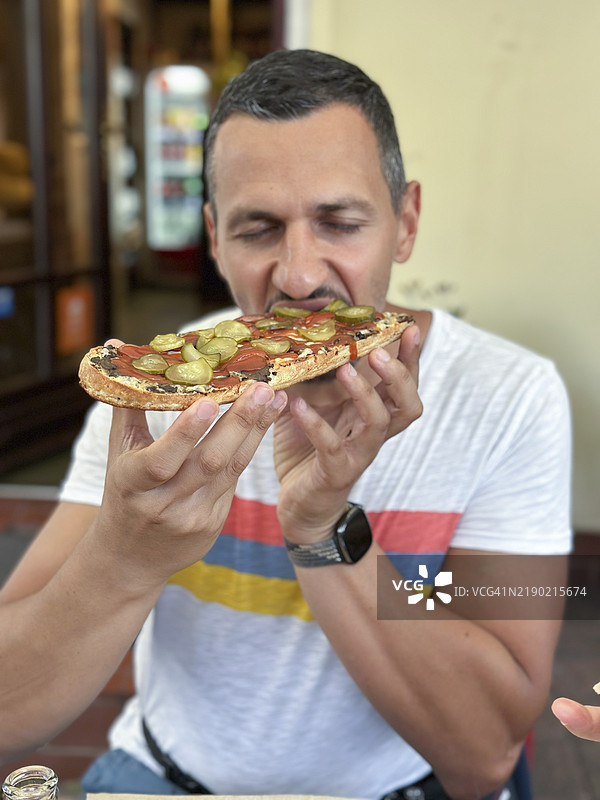 正面视角的男子正在享用典型的波兰烤法棍zapiekanka。图片素材