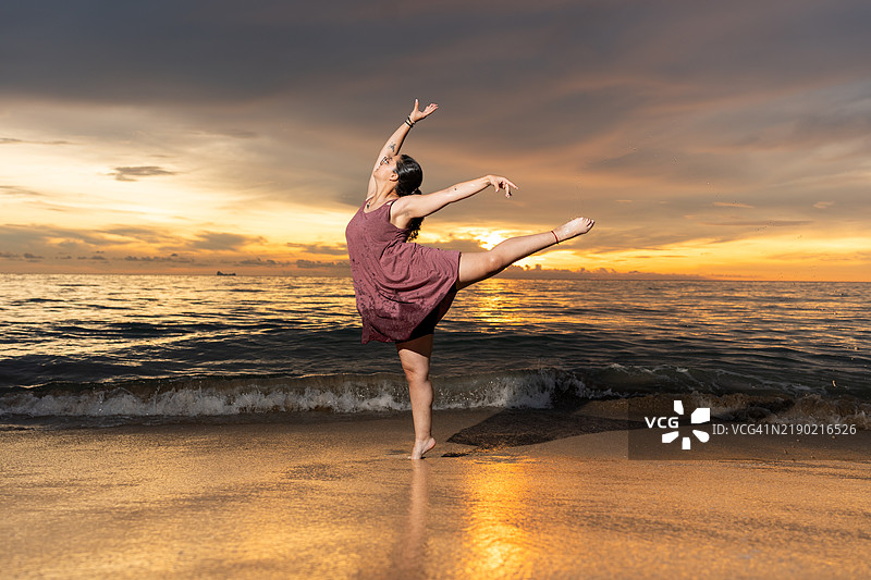年轻女性在泰国海滩日落时跳舞图片素材