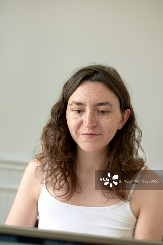 一位女性坐在笔记本电脑前，专注于她的工作，面带沉思的表情图片素材