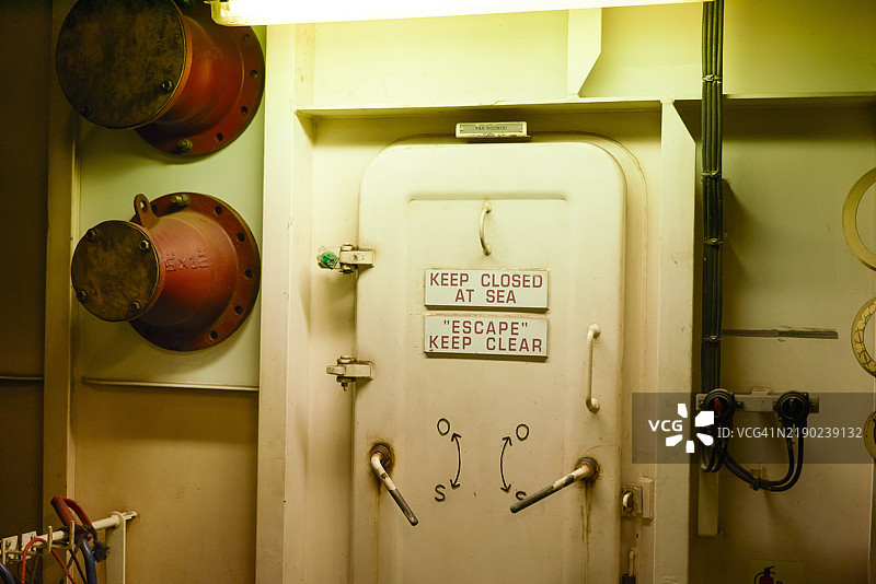 船上的防水门，安全指示标语为“海上保持关闭”和“逃生”，以确保安全和紧急意识。图片素材