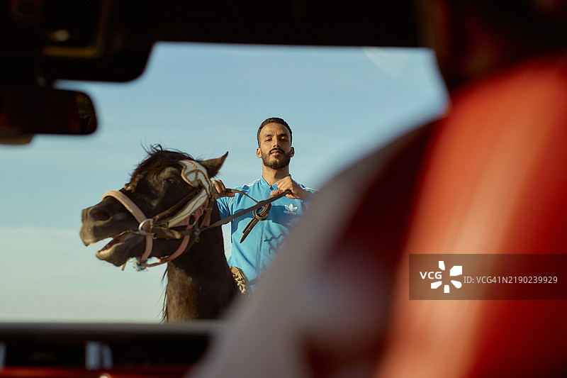 在摩洛哥，透过汽车挡风玻璃看到一名骑马的人手握缰绳，天空晴朗。图片素材