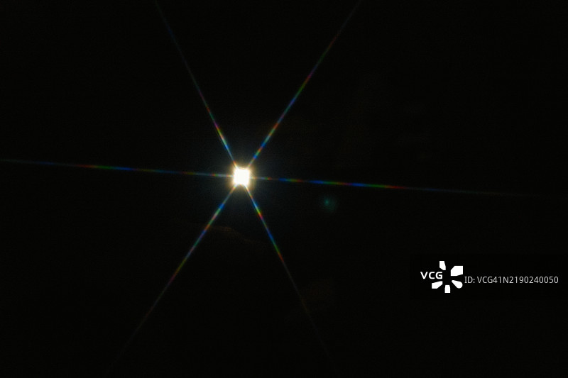 明亮的星光爆发效果，带有彩色衍射光带，背景为黑色图片素材