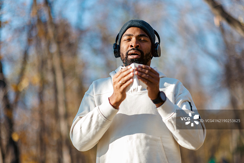 年轻男子在户外锻炼时擤鼻子图片素材