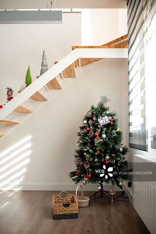 装饰着红色和银色饰品的圣诞树矗立在现代住宅中图片素材