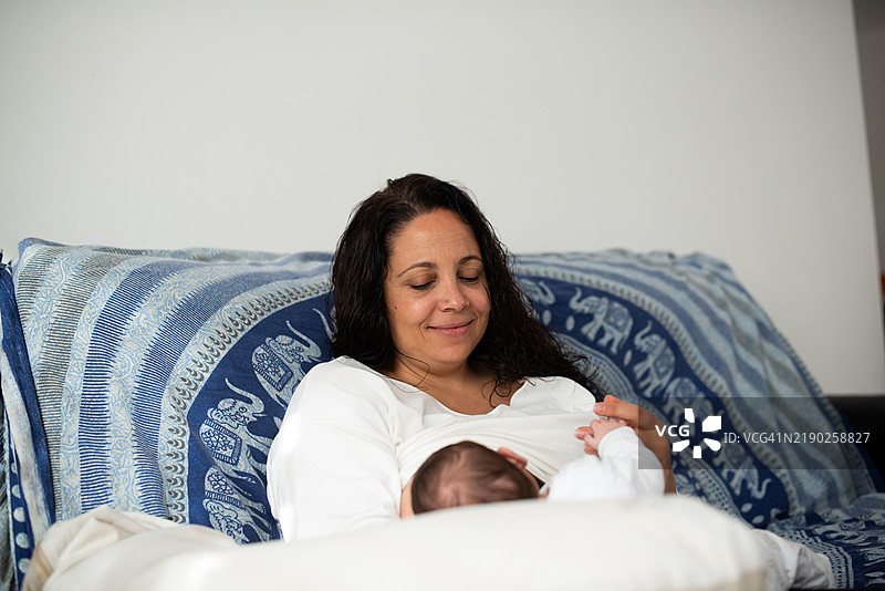 母亲在家沙发上哺乳她的新生儿图片素材