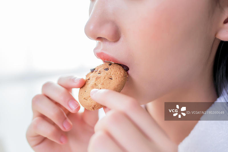 年轻女性特写，正在吃巧克力曲奇饼干图片素材
