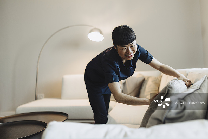 女佣在家中清洁和整理沙发垫图片素材