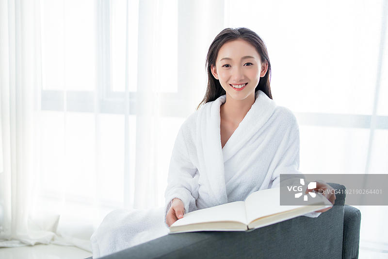 一位年轻女性正在客厅的沙发上阅读一本书图片素材