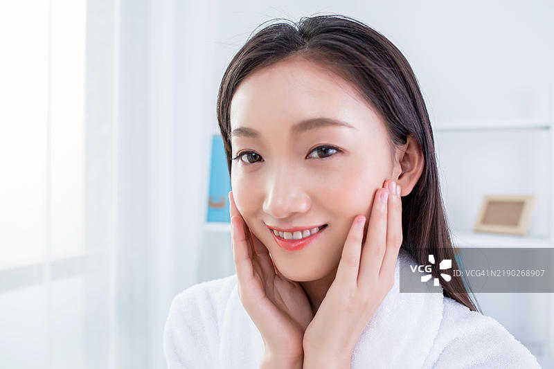 亚洲女性面带愉悦表情触摸自己的脸颊图片素材