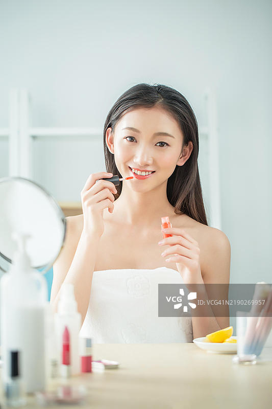 亚洲女性在镜子前涂口红图片素材