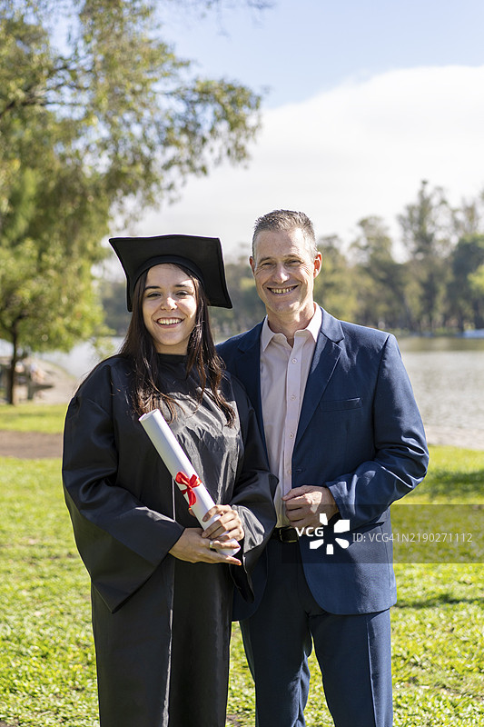 穿着学位服和学位帽的女毕业生在校园里与家人庆祝图片素材