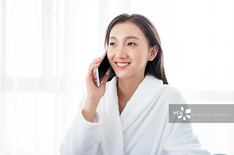 穿着浴袍的亚洲女性微笑着打电话图片素材