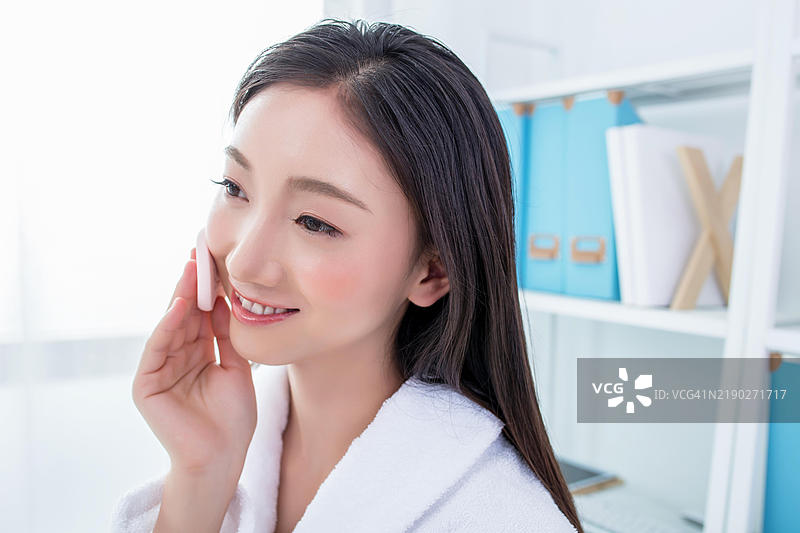 亚洲女性在涂抹面部粉末图片素材