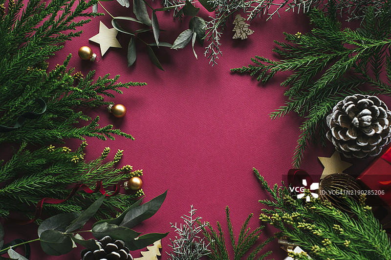 自然的圣诞背景，俯视平铺。红色背景上的松树绿枝和装饰品图片素材