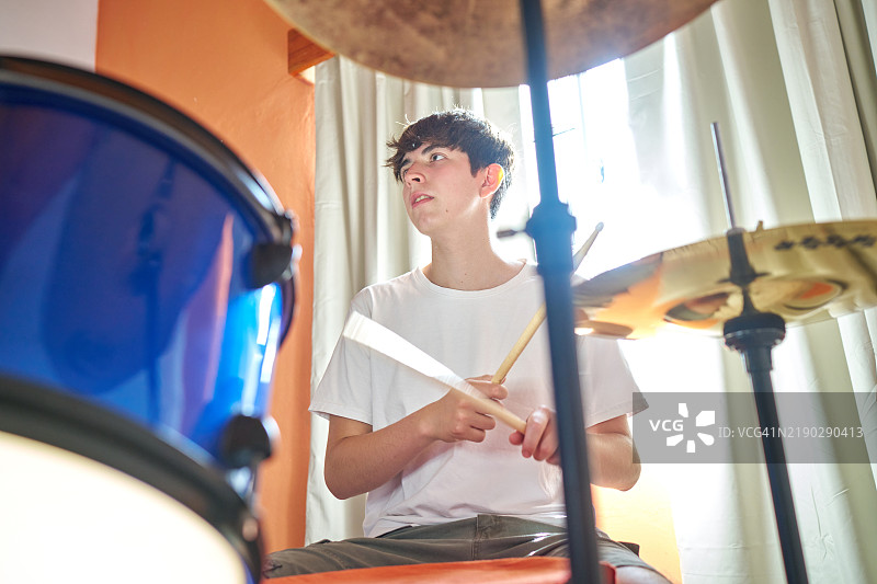 年轻男性音乐家用鼓棒演奏鼓乐图片素材