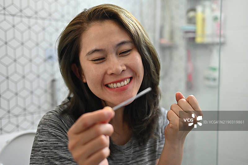 快乐的女性在使用LH排卵测试条。测试条提供准确清晰的怀孕可能性结果。图片素材