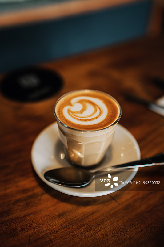 侧面视图的皮科洛拿铁咖啡杯，放在碟子上，旁边有一把勺子图片素材