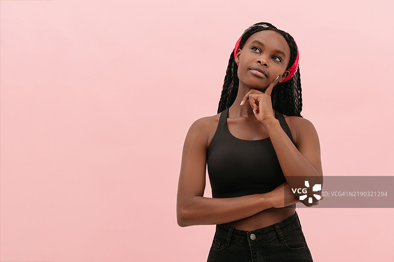 思考中的年轻女性，粉色背景。留白空间。图片素材