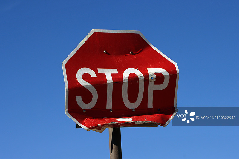 受损的停车标志特写，背景是蓝天图片素材