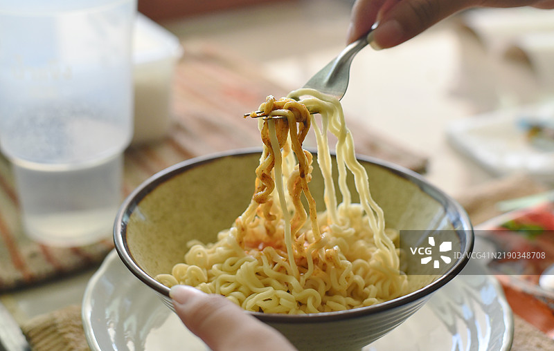手拿叉子在碗中旋转方便面特写镜头图片素材