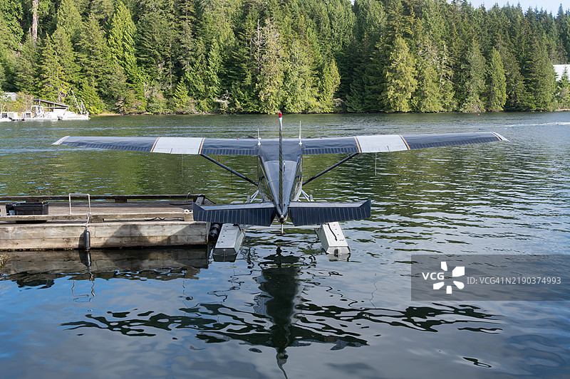 从后方看一架停靠在码头的水上飞机，附近是温哥华岛班菲尔德的沿海森林，加拿大不列颠哥伦比亚省。图片素材