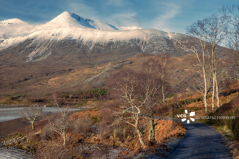 克莱尔湖旁的道路，苏格兰高地。阳光照耀着贝因艾赫山。图片素材