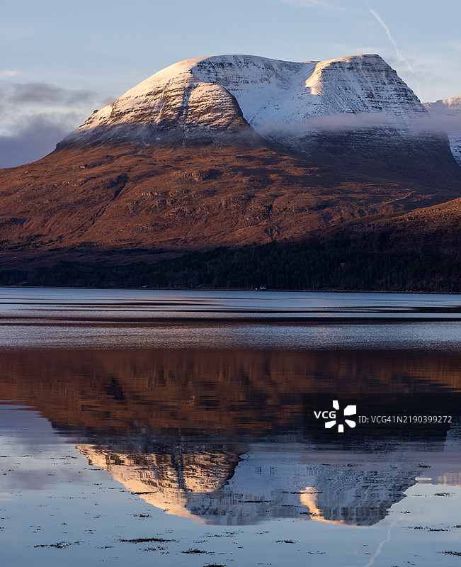 贝因阿利金山和利亚塔赫山在冬末阳光下的托里登湖静谧的水面上倒影，山峰上覆盖着雪。图片素材