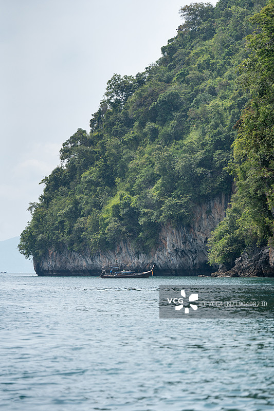 在泰国的郁郁葱葱的热带岛屿附近，传统的长尾船正在航行。图片素材
