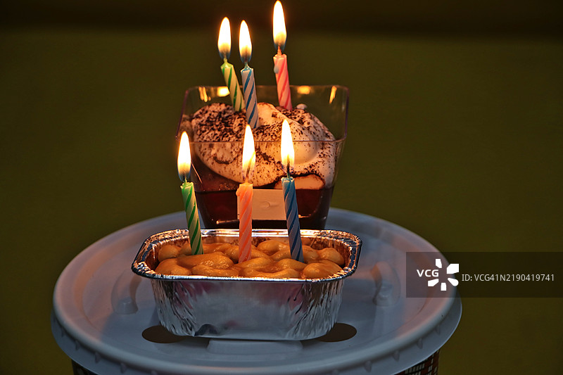 小方形容器中的蛋糕上点燃了蜡烛图片素材