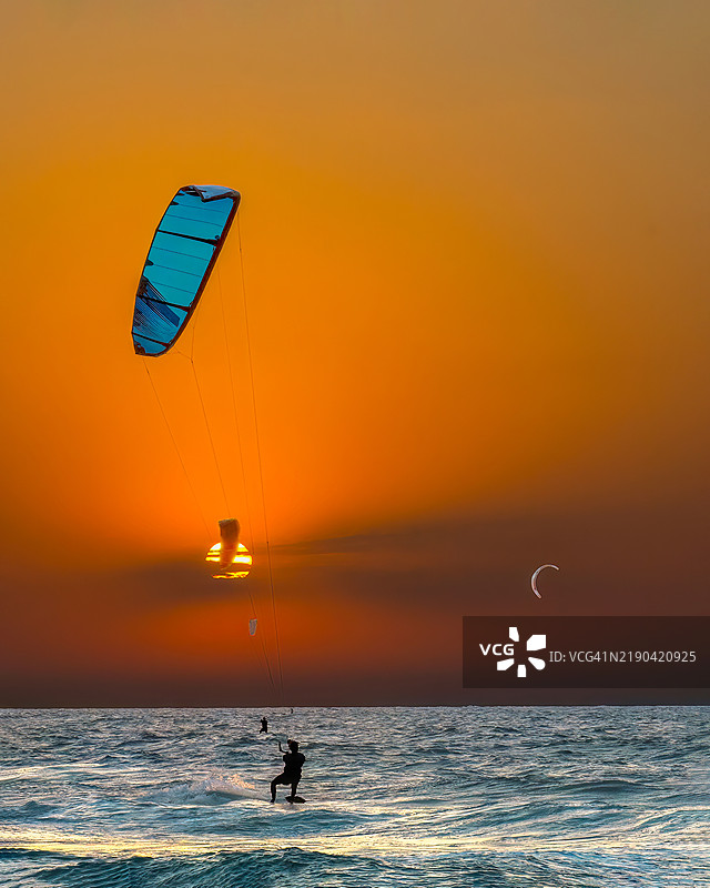 男子在日落时分于海上滑翔冲浪，背景是天空。图片素材