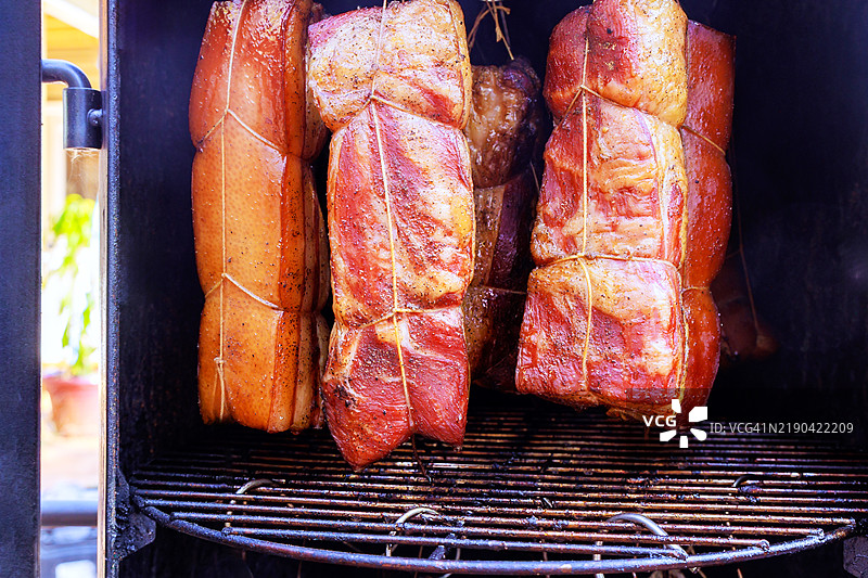 烟熏器内悬挂着各种切割的培根，挂在钩架上图片素材