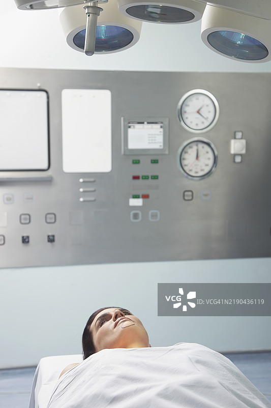女性躺在手术台上，接受检查灯的照射图片素材