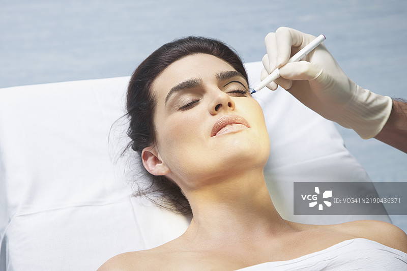 医生的手用笔在女性眼睑上标记图片素材